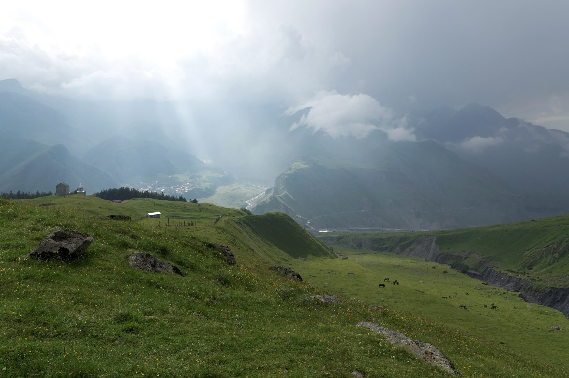 "Kazbegi", Mount Kazbek range obscured by clouds and rays of setting sun, Georgia
